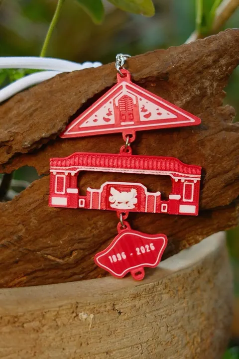 Cận cảnh thẻ khóa: mái ngói, cổng trường và mảnh 1896 - 2026
